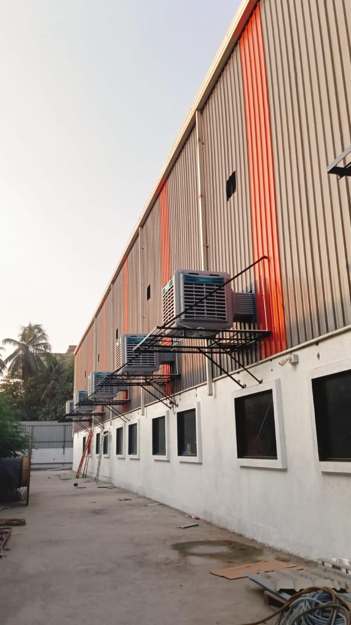 Wall-mounted industrial air coolers installed along the length of a factory shed.