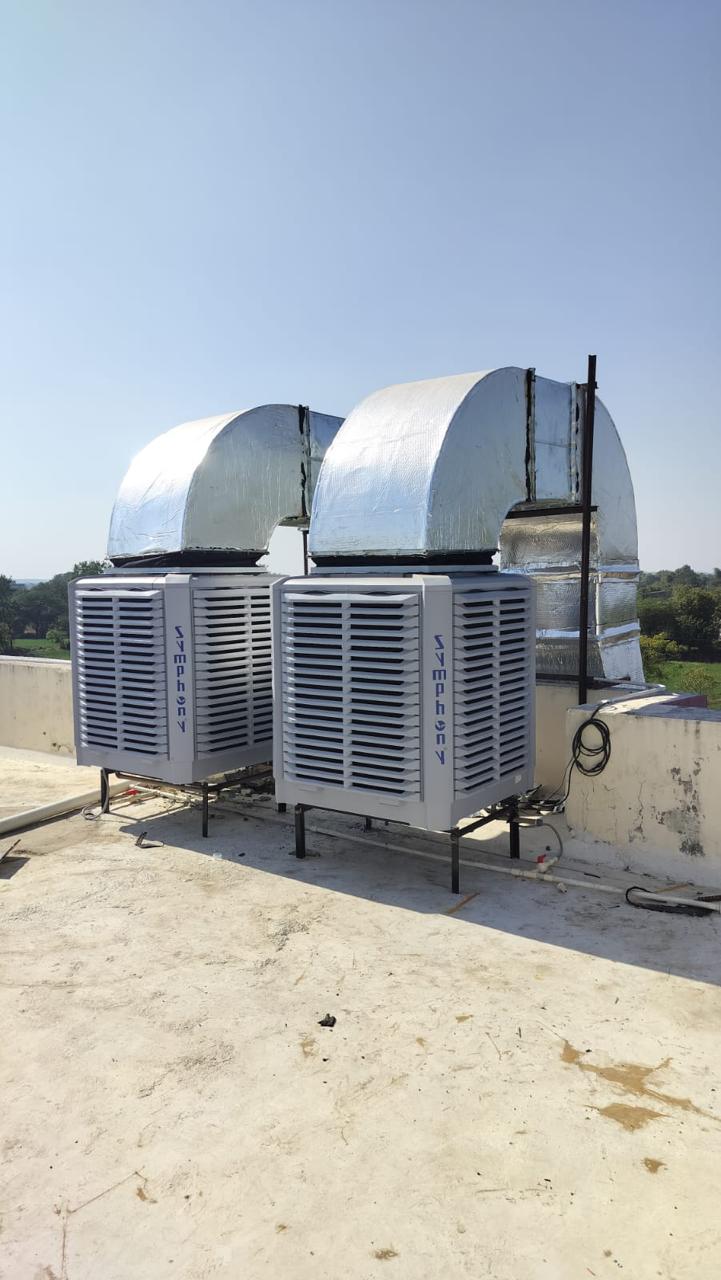 Two Symphony industrial air coolers with fabricated GI duct hoods on a building terrace.