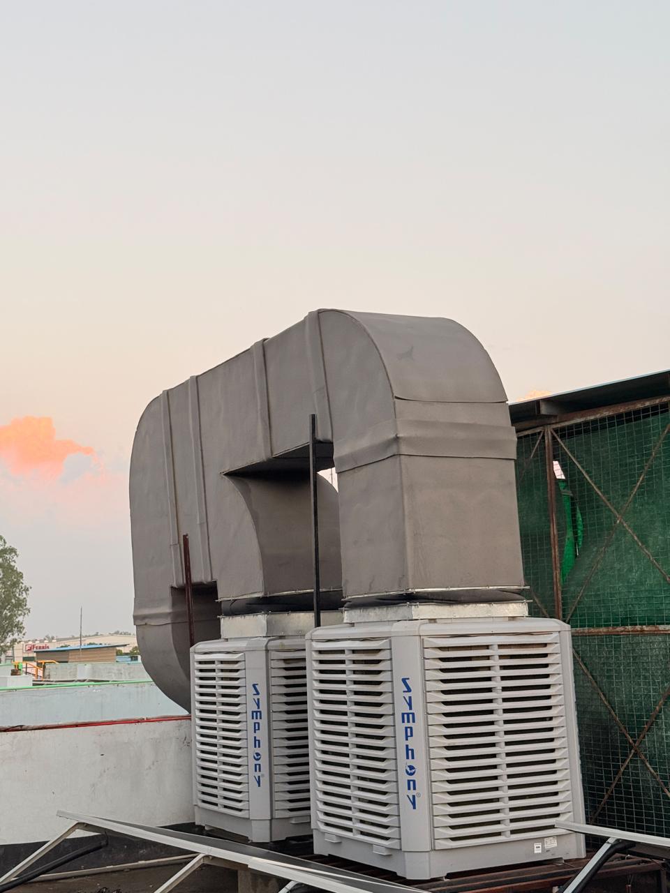 Twin rooftop air coolers connected to GI ducting for an industrial unit.